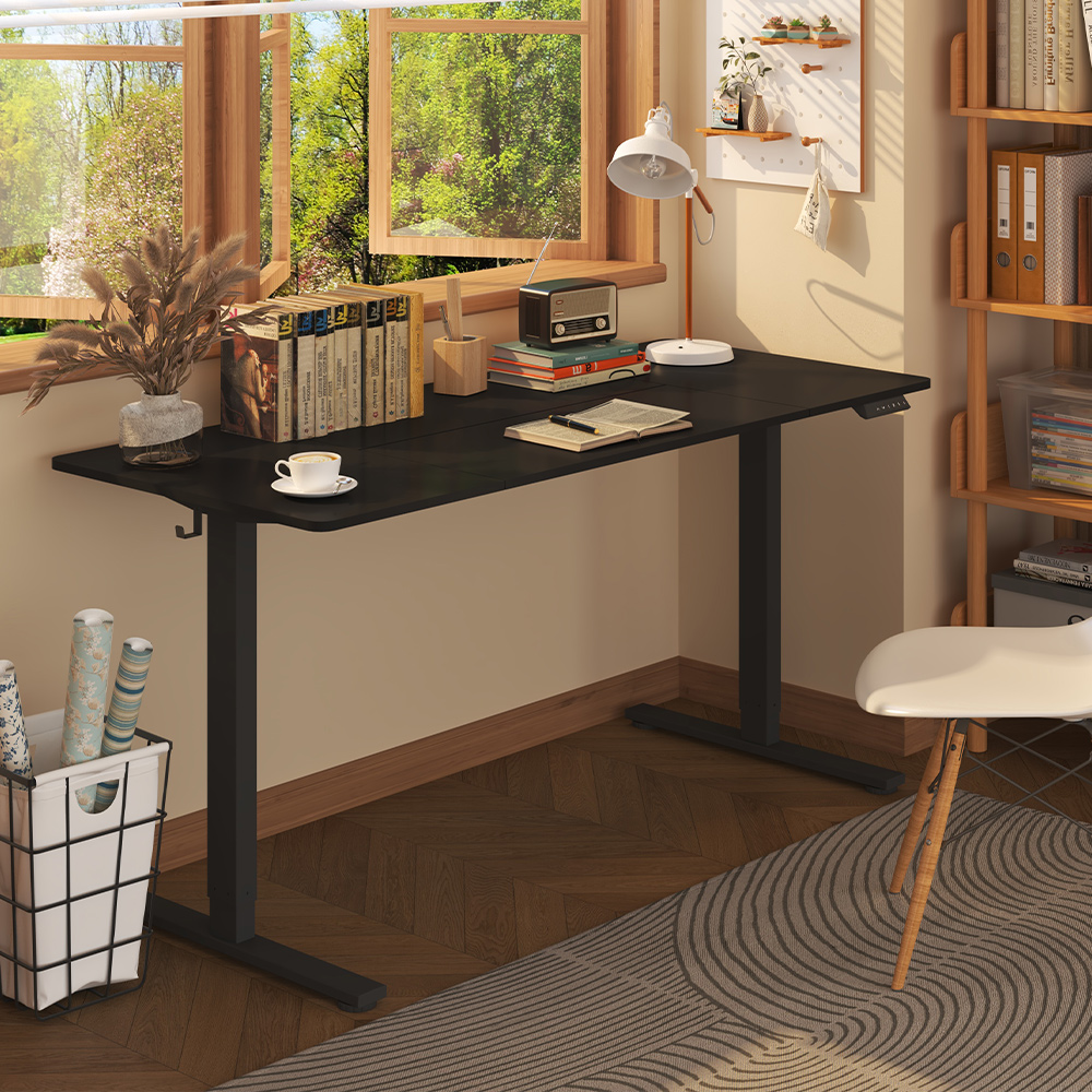 A black electric height-adjustable standing desk frame paired with a black desktop in a cozy, sunlit home office