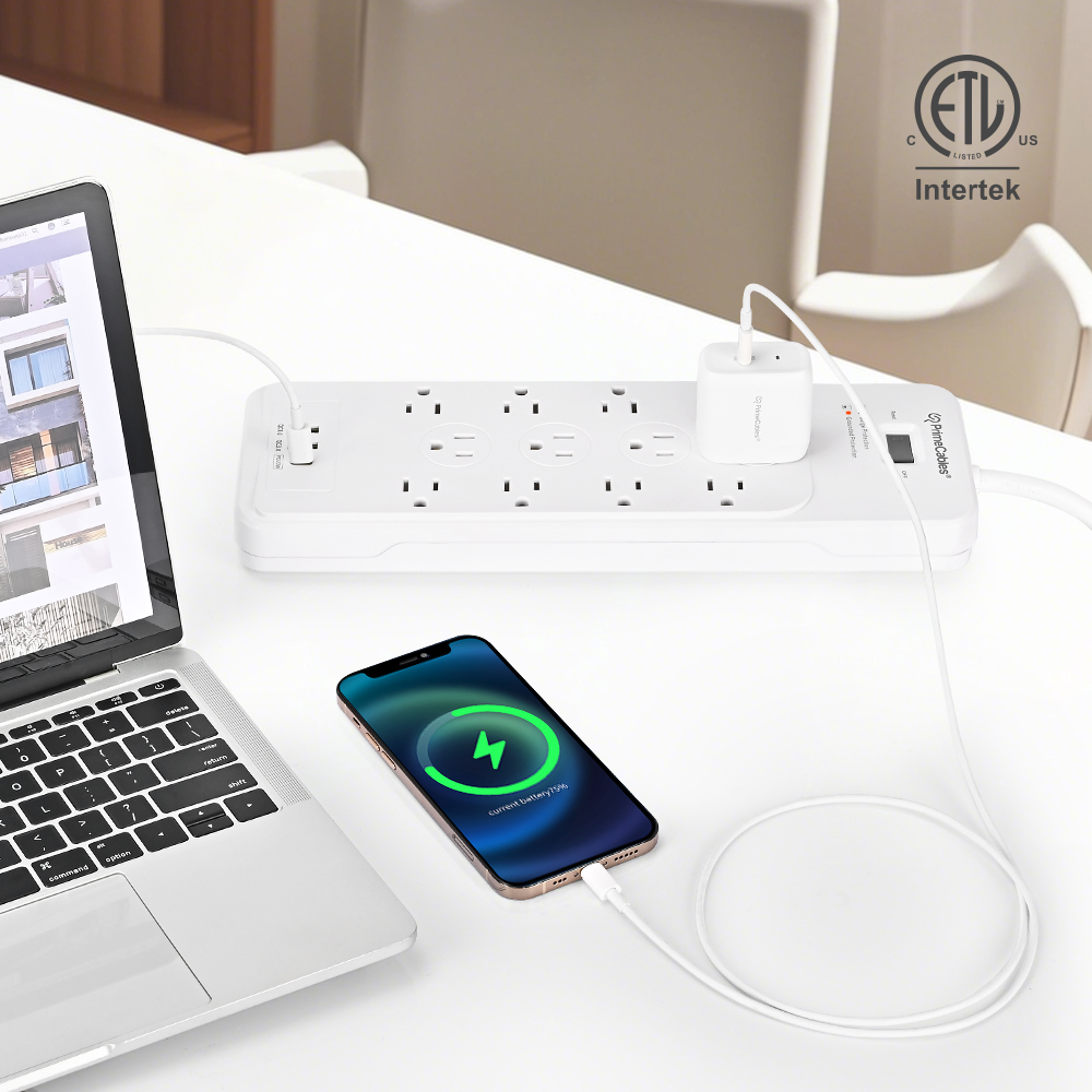 This PrimeCables white surge protector power strip is powering a laptop and a smartphone on the desk