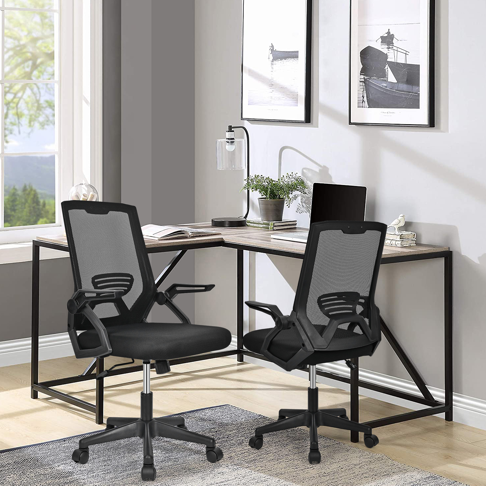 Two black mesh office chairs placed beside an L-shaped wooden desk inside a bright home office room