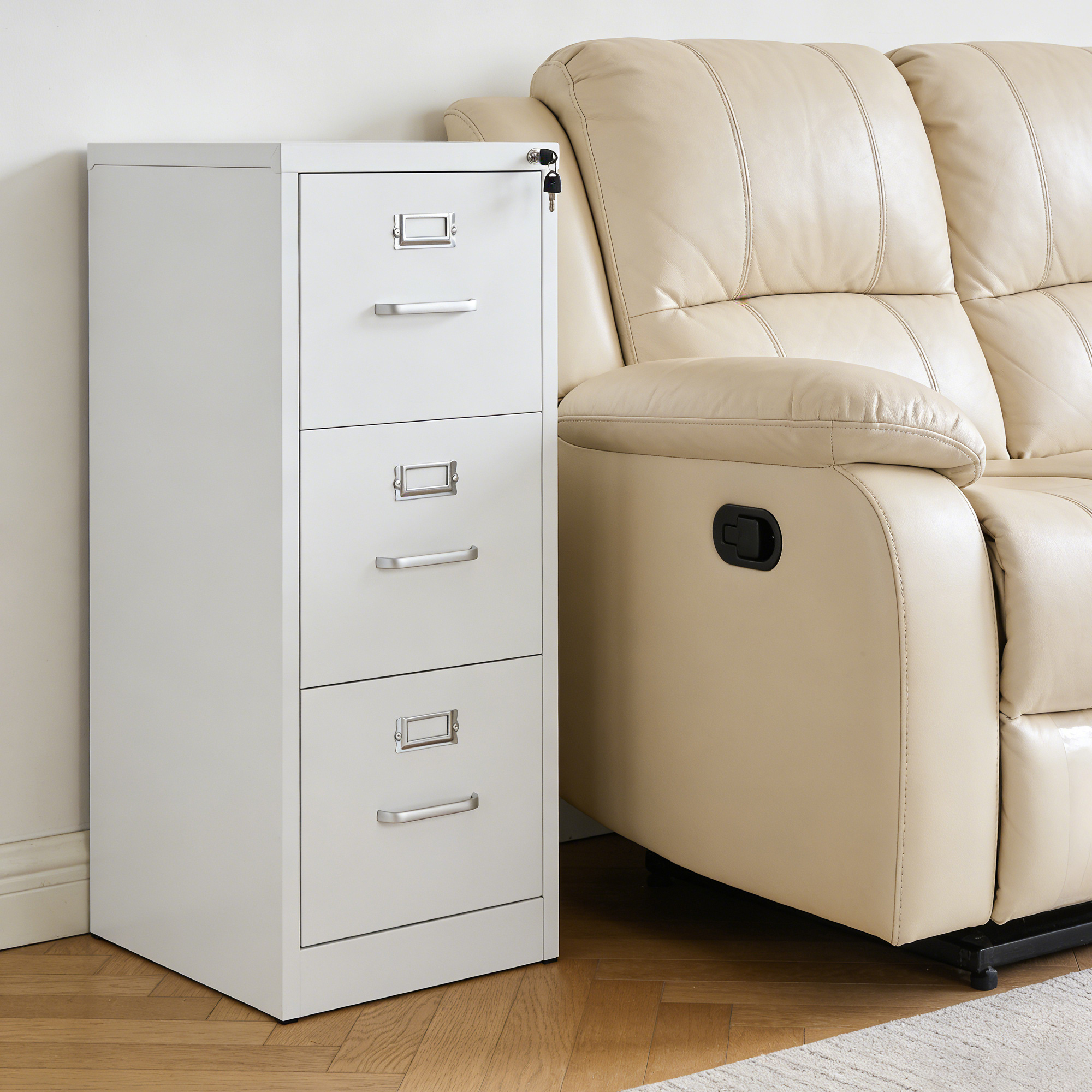 White lockable 3-drawer vertical metal file cabinet positioned next to beige leather recliner sofa in the living room