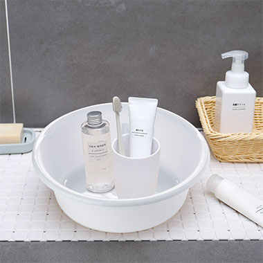 brosse à dents, dentifrice, gobelets de salle de bain et nettoyant pour le visage dans un bassin