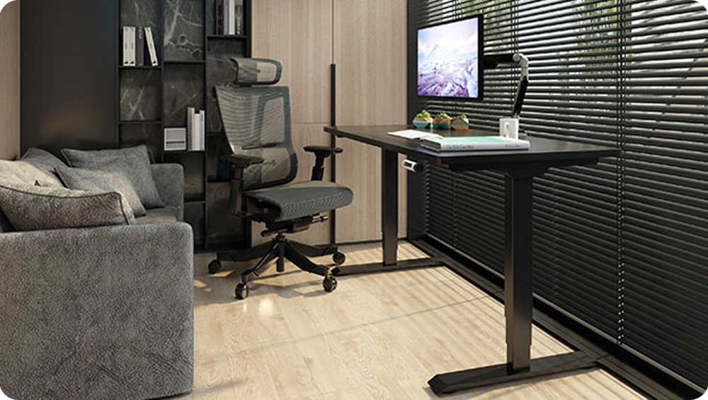 Black standing desk tabletop mounted on a sit-to-stand desk frame in a modern office